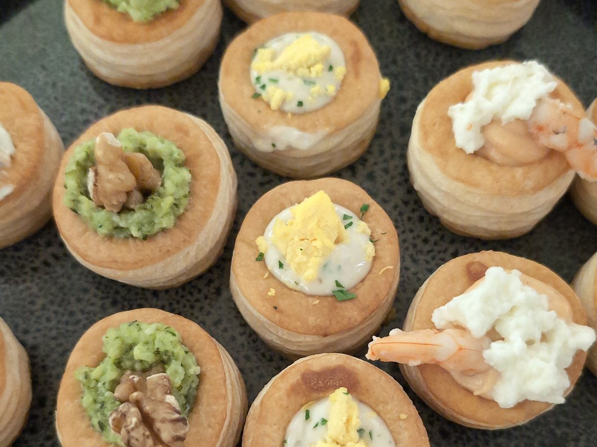 Vol-au-vent di sfoglia con crema verde e noci, salsa bianca con uovo sodo, gamberi e formaggio fresco su piatto scuro